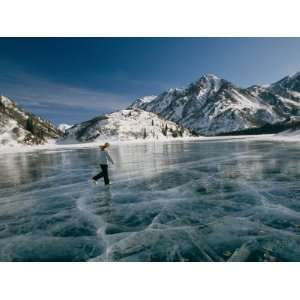  A Girl Ice Skates Across a Frozen Mountain Lake Stretched 